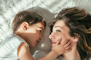Fototapeta na wymiar top view of cute toddler boy touching face of attractive mother