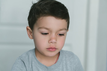 thoughtful toddler boy looking down at home