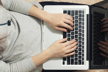 Fototapeta premium Girl working on a laptop at home on the couch. Freelance and Remote Quarantine Concept, top view