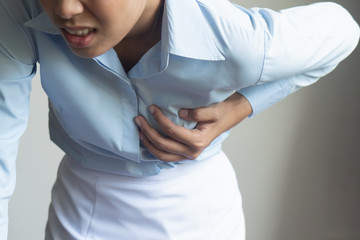 woman with sudden heart attack; sick woman suffering from acute heart attack, concept of emergency health care; young adult woman model