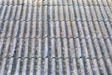 Close-up view of old wavy slate roof with moss. Texture of old slate with moss. Shed roof covered with old asbestos sheets. Outdoor interior. Texture of old roof, slate background