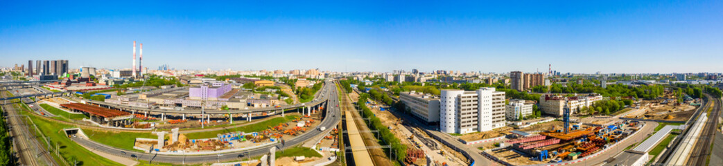 Fototapeta premium Power plant pipes and cooling towers in Moscow from above, automobile traffic and and construction of a new car overpass and interchange in the Moscow industrial zone near the automobile ring highway