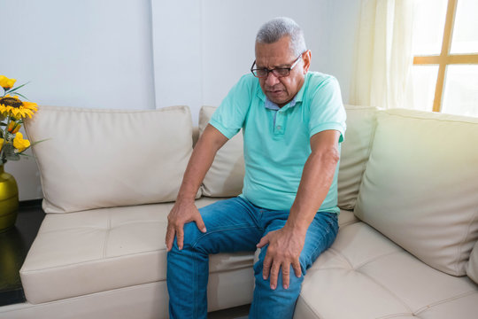 people, health care and concept medical problem - unhappy older man suffering from leg pain at home
