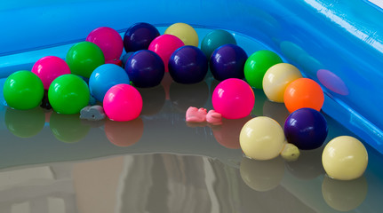 The blue inflatable pool inside has many colored balls.