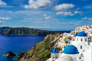 Blue-domed churches near white houses and sea in Santorini