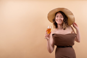 Young woman in straw hat with orange drink dreaming about vacation on sea