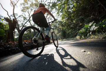 Woman cycling on bike path at park on sunny day