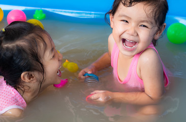 Two kindergarten girls in Asia play in the inflatable pool.