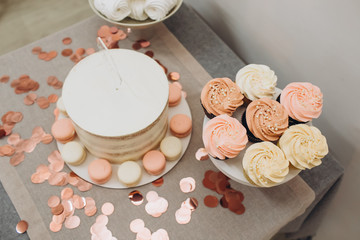 Birthday cake. Garland - happy birthday, hanging on the wall. Candy bar with cake, marshmallows, and cupcakes. Stylish decor for a children's party.