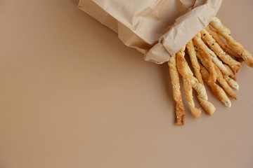 Crispy snack in a paper bag. Salty sesame bread sticks for a quick bite
