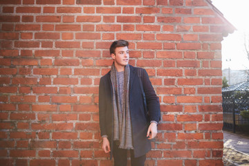 Cheerful stylish man standing near brick wall on street