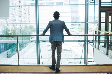 Elegant man standing near window in modern building