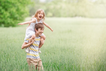 Fototapeta premium Two children a boy and a girl together in the open air outside the city, tenderness towards each other. A brother and sister play in a field in the open air in the village. 