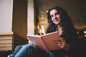 Obraz premium Young woman reading book in library