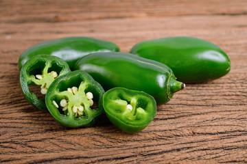 whole and portion cut fresh Jalapeno or Mexican Chili on wooden background