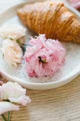 Obraz na płótnie Canvas Croissant on a white plate with flowers. Nice breakfast. Concept of coffee shop and flower shop.
