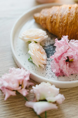 Croissant on a white plate with flowers. Nice breakfast. Concept of coffee shop and flower shop.