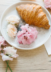 Croissant on a white plate with flowers. Nice breakfast. Concept of coffee shop and flower shop.