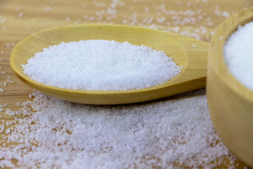 Monosodium glutamate in spoon on wooden table.