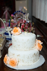 There are yellow flowers on the cake. The letter U and R are written in gold on the cake . White Two-tiered cake .