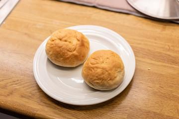 Freshly baked chocolate filled buns on a white plate.