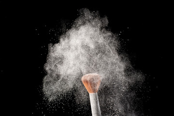White powder splash with make up brush blusher isolated on white background.
