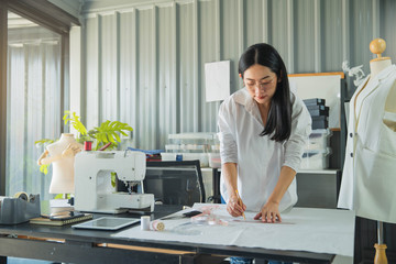 Young female fashion designer working on her designs in the studio. Fashion designer drawing...