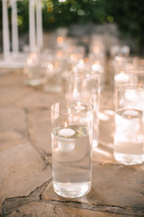 Many flasks with water. Tea lights float in a flask