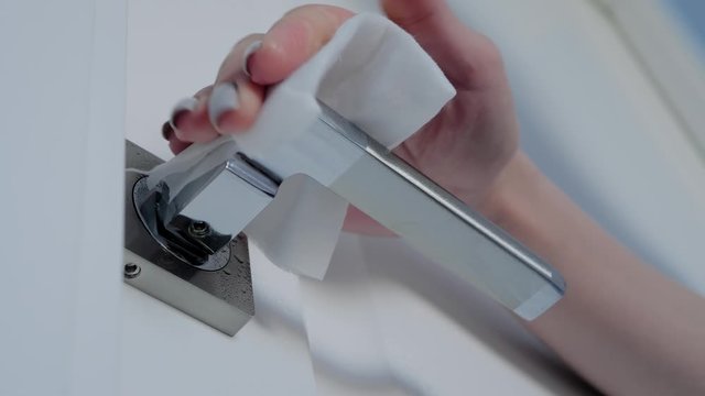 Disinfection, protection, prevention, housework, COVID 19, coronavirus, safety, sanitation concept. Slow motion: woman cleaning door handle with antiseptic disinfectant wet wipe - low angle close up