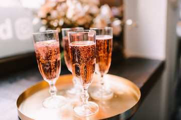 Four glasses with champagne stand on a golden tray