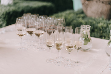 Many glasses with champagne are on the table. The table is covered with a white tablecloth