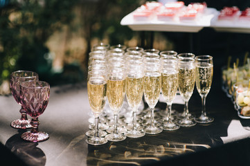 Many glasses with champagne are on the table. The table is covered with a white tablecloth