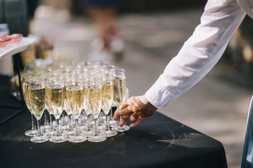 Many glasses with champagne are on the table. The table is covered with a white tablecloth