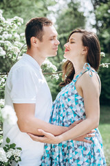 Young parents walk in the park on a warm spring day. Pregnant young woman in nature. Happy future parents. Waiting for a miracle.