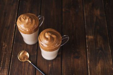 Top view of two glasses with famous coffee Dalgona on dark wooden table
