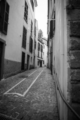 A narrow European street isolated in the period of pandemic covid-19. Black and white photo of deserted narrow street with old architecture in the period of self-isolation. Paving stones. Stay home