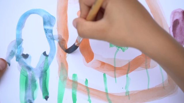 Closeup view video footage of cute little boy of 5 years old painting outdoors. Child paints cute house and funny blue bunny.