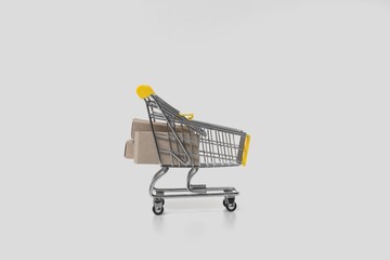 A small basket with goods in paper cardboard boxes. The concept of selling goods over the Internet on a white background isolated