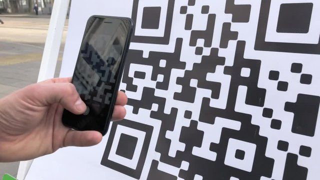Scanning QR code with smart phone. The man reads the bar code using the application on the smartphone.