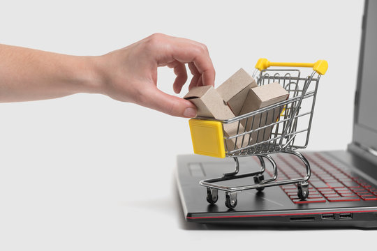 The woman's hand takes a paper box from the grocery basket. The concept of delivering goods from an online store to a home