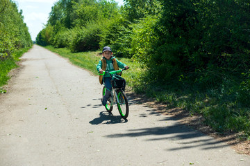 Naklejka premium Boy on bicycle at summer asphalt road. Kid cycling outdoors. Summer sport activity concept. Soft focus