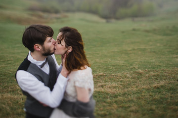 Romantic, young and happy caucasian couple in wedding clothes hugging on the background of beautiful mountains. Love, relationships, romance, happiness concept. Bride and groom traveling  together.