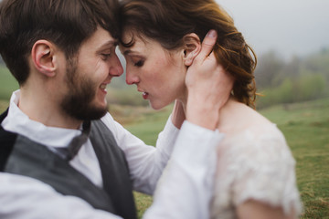 Romantic, young and happy caucasian couple in wedding clothes hugging on the background of beautiful mountains. Love, relationships, romance, happiness concept. Bride and groom traveling  together.