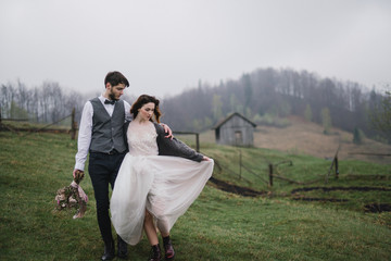 Romantic, young and happy caucasian couple in wedding clothes hugging on the background of beautiful mountains. Love, relationships, romance, happiness concept. Bride and groom traveling  together.