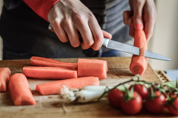 Peeling carrots close up. Girly hands preparing food in the kitchen.