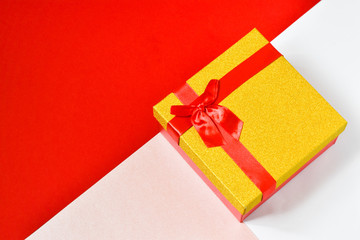 Beautiful gift box with ribbon bow on a red and white background. Place for text.