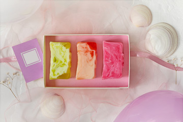 Pieces of homemade organic natural flower soap in a gift box with ribbon, postcard with place for inscription and balloons. Concept of eco natural bathroom cosmetics product. handmade soap as a gift
