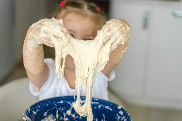 Baby kneads dough in a saucepan