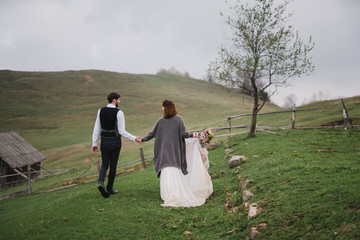 Romantic, young and happy caucasian couple in wedding clothes hugging on the background of beautiful mountains. Love, relationships, romance, happiness concept. Bride and groom traveling  together.