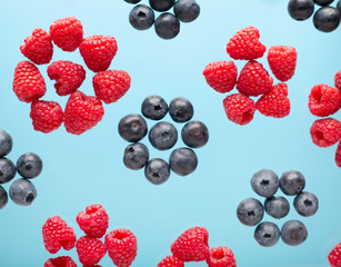 Berries on a blue background. Flying raspberry and and blueberries